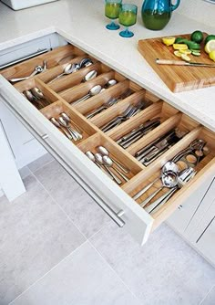 an open drawer in the middle of a kitchen with utensils and spoons