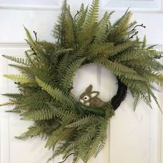 a wreath with an animal in the center and ferns around it, hanging on a door