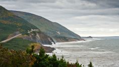 a scenic view of the ocean and coastline from a hill side area with trees on both sides