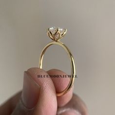 a person holding a gold ring with a diamond on it