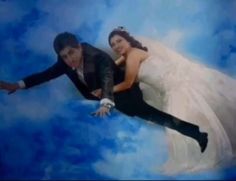 a bride and groom are flying through the air in their wedding photo shoot with blue clouds behind them