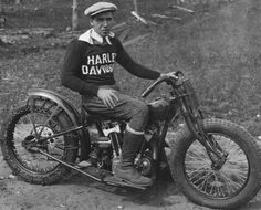 a man sitting on top of a motorcycle in the dirt with his hand on the wheel