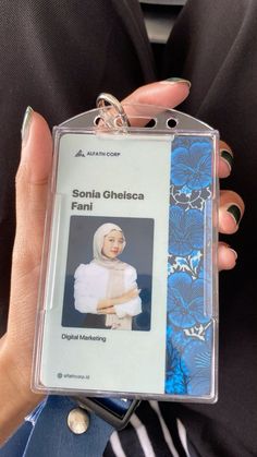 a person holding up a plastic badge with a woman's face on it in front of her