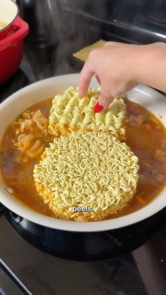 someone using a sponge to scrub down noodles in a bowl on top of the stove