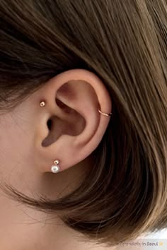 a woman's ear is shown with two piercings on the top of it