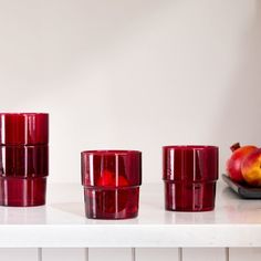 red glass cups sitting on top of a white counter