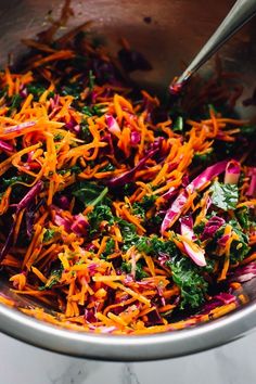 a bowl filled with shredded carrots and greens