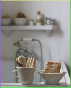 two cups with toothbrushes and soap in them sitting on a kitchen counter next to a sink