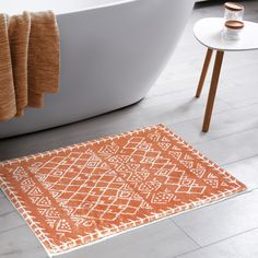 an orange and white bathroom rug in front of a bathtub