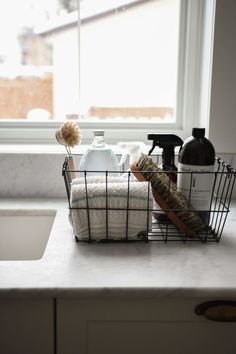 a kitchen counter with soap, dish towels and other items in a basket on it