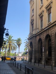 an empty city street with palm trees and tall buildings on both sides in the background