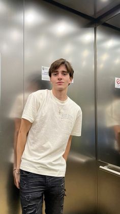 a young man standing in front of a stainless steel wall