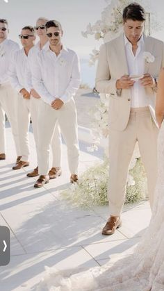 the bride and groom are looking at each other as they stand in front of their wedding party