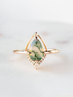 a gold ring with a green and white stone in the center