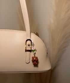 a white handbag hanging from the side of a wall with feathers in the background