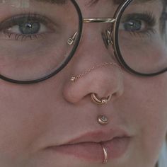 a close up of a person wearing glasses with nose rings and piercings on their nose