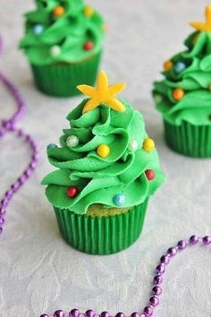 cupcakes decorated with green frosting and christmas tree decorations on a white tablecloth