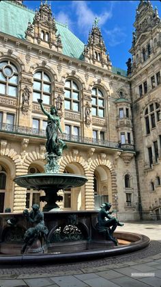 a fountain in front of a large building with statues on it's sides and windows