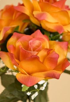 orange and yellow roses in a vase with baby's breath on the inside side