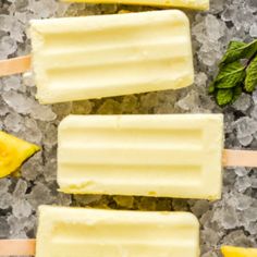 three popsicles sitting on top of ice next to bananas and minty sprigs