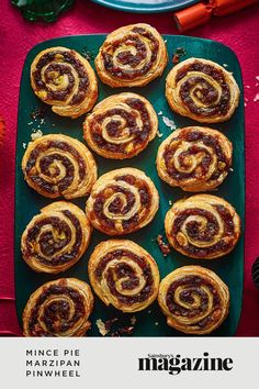 several cinnamon rolls on a green plate with red cloth and orange flowers in the background