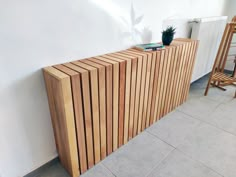 a wooden cabinet sitting on top of a tiled floor next to a chair and radiator