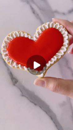 someone is holding a heart shaped cookie in their hand and it looks like they are eating something