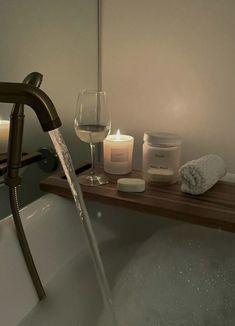 a bathtub filled with water next to candles and soaps on a wooden tray