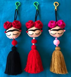 three different colored tassels hanging from hooks on a blue cloth covered surface,