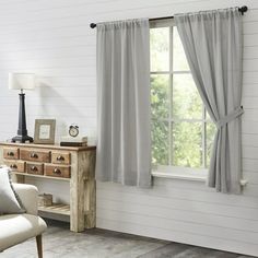 a living room with a couch, chair and large window covered in gray drapes