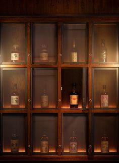 an assortment of liquor bottles on display in a wooden case with glass doors and shelves