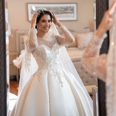 a woman in a wedding dress looking at herself in the mirror with her hand on her head