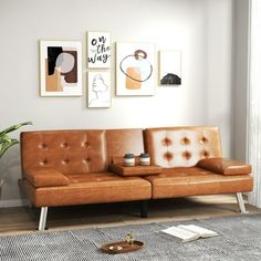 a brown leather couch sitting on top of a wooden floor next to a potted plant