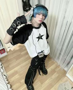 a person with blue hair wearing headphones and black pants standing on a wooden floor