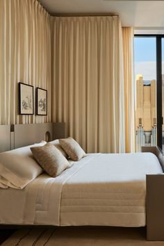 a bedroom with a large bed next to a window and a view of the city