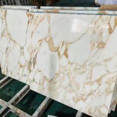 white marble with gold veining on pallets in a factory room, ready to be polished