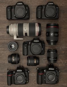 many different cameras sitting on top of a wooden table