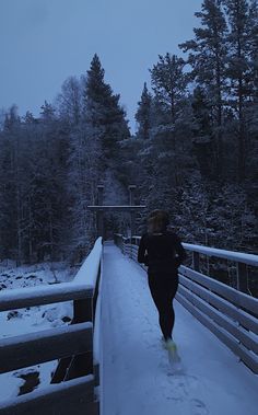 a woman running across a bridge in the snow