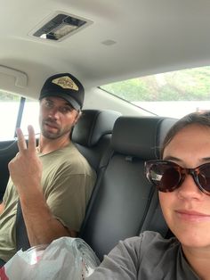 a man and woman sitting in the back seat of a car with their fingers up