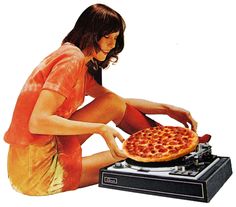 a woman sitting on the ground with a pizza in front of her and an old record player