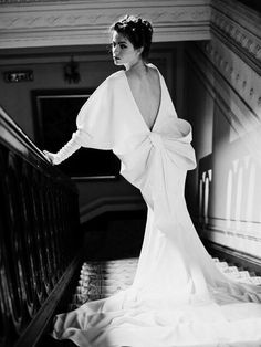 a woman in a long white dress leaning on a rail with her hand on the railing