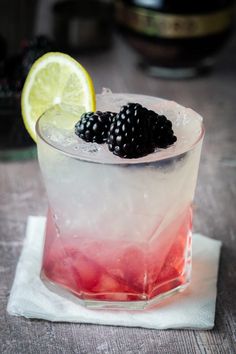 a drink with blackberries and lemon on the side