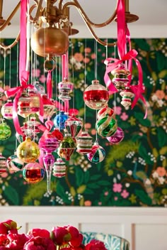 a chandelier filled with ornaments hanging from it's sides in front of a floral wallpaper