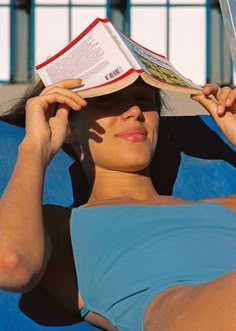 a woman laying in a chair with a book on her head and reading the same book