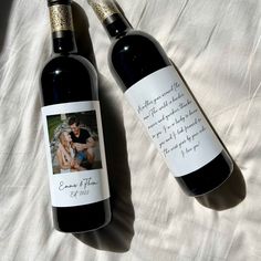 two bottles of wine sitting next to each other on a white sheet covered bedding