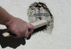 a person holding a brush near a hole in the wall