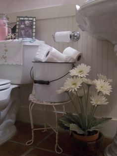 a white toilet sitting in a bathroom next to a sink and a tub filled with flowers