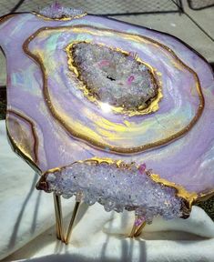 a purple and gold plate sitting on top of a white cloth