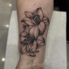 a woman's leg with a flower tattoo on it and the word mum written in cursive font