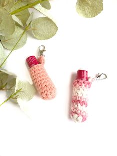 two crocheted items are sitting next to each other on a white surface with green leaves